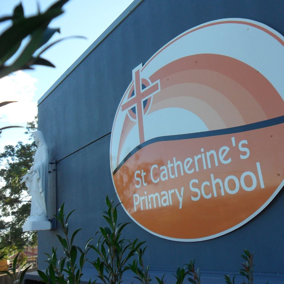 Image of St Catherine statue and school logo from front face of Administration building