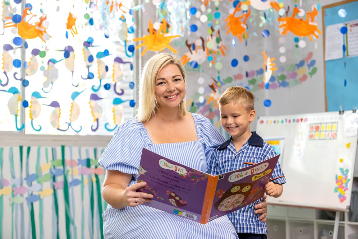 Image of teacher reading a book to a student. Both are smiling
