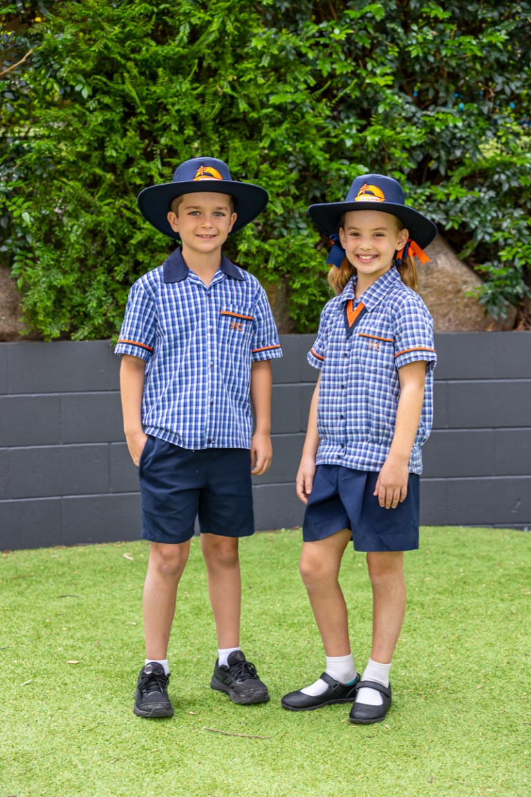 Image of two students in the formal checked shirt school uniform including hats.
