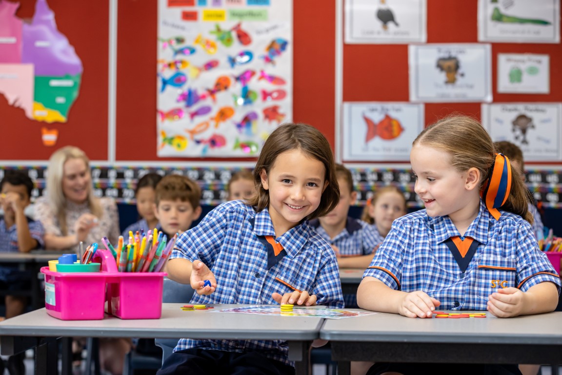 Image of two students working in class, smiling