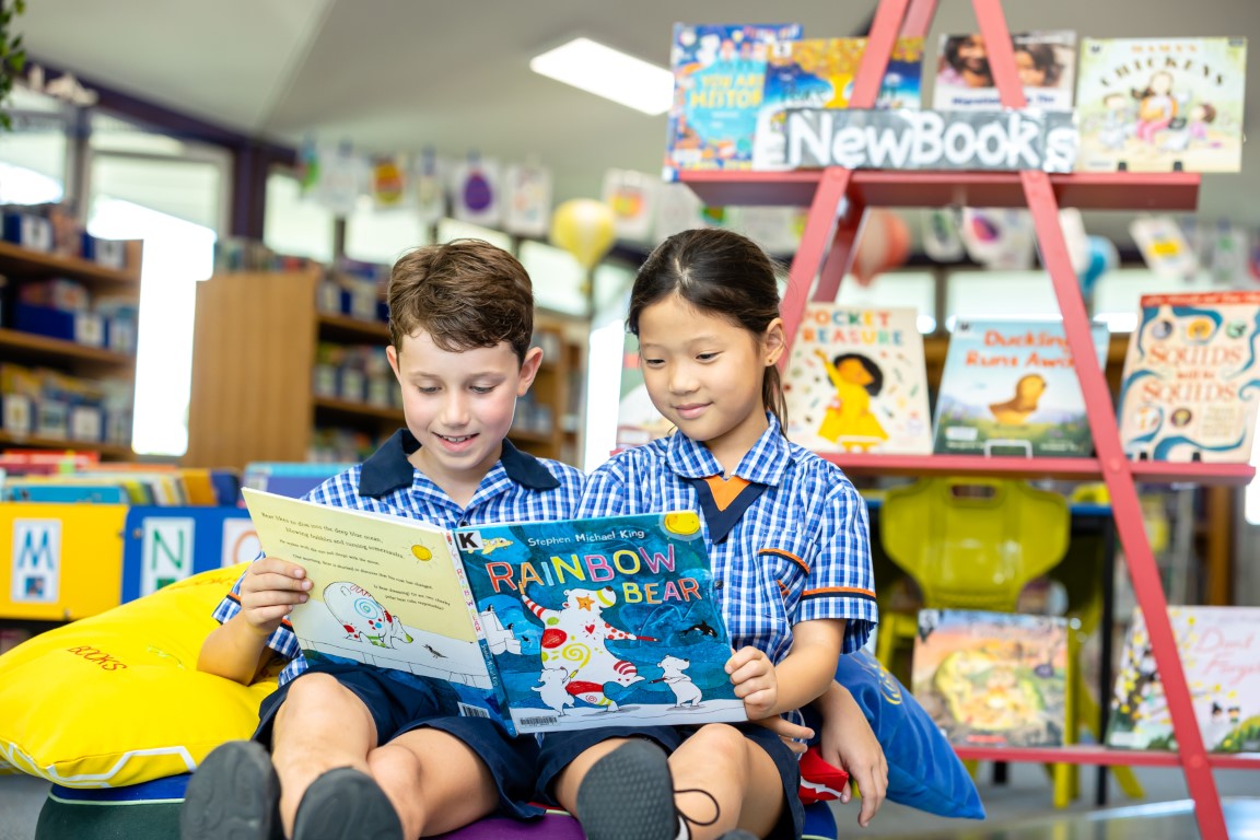 Two students reading a book in the Library.